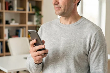 Homme tenant un smartphone Samsung S22 à une main dans un bureau moderne, vue trois-quarts